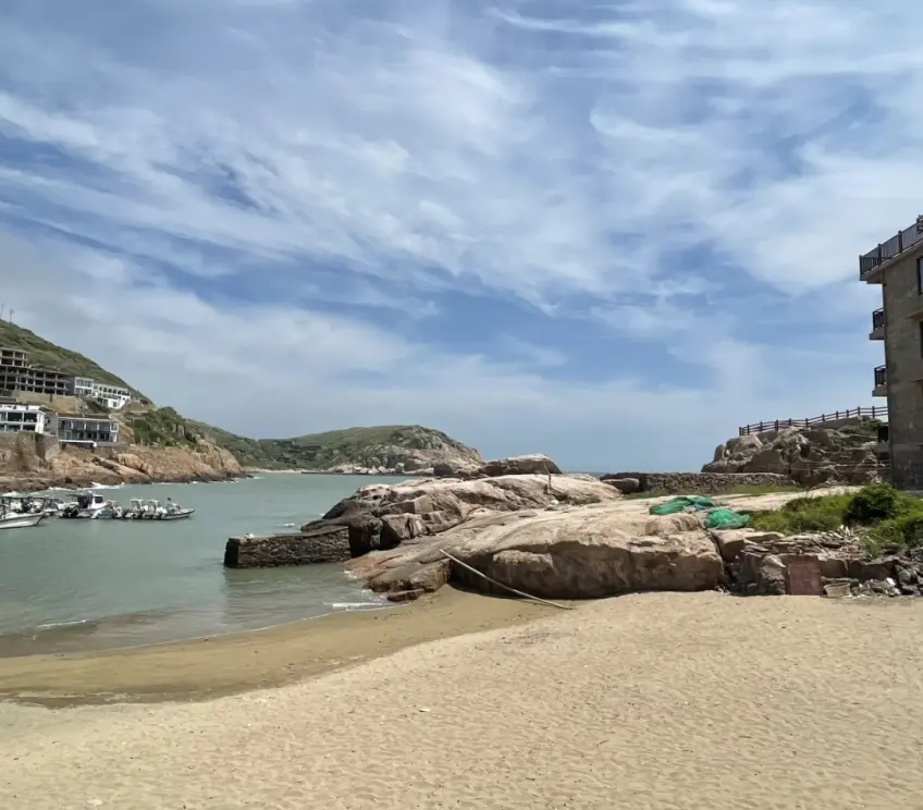 細沙海灘白船與對岸山丘