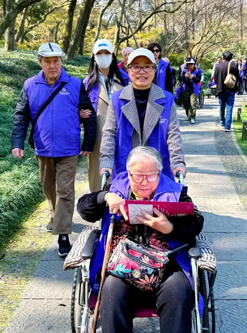 豎向示意：景區石徑上助推輪椅的長輩團