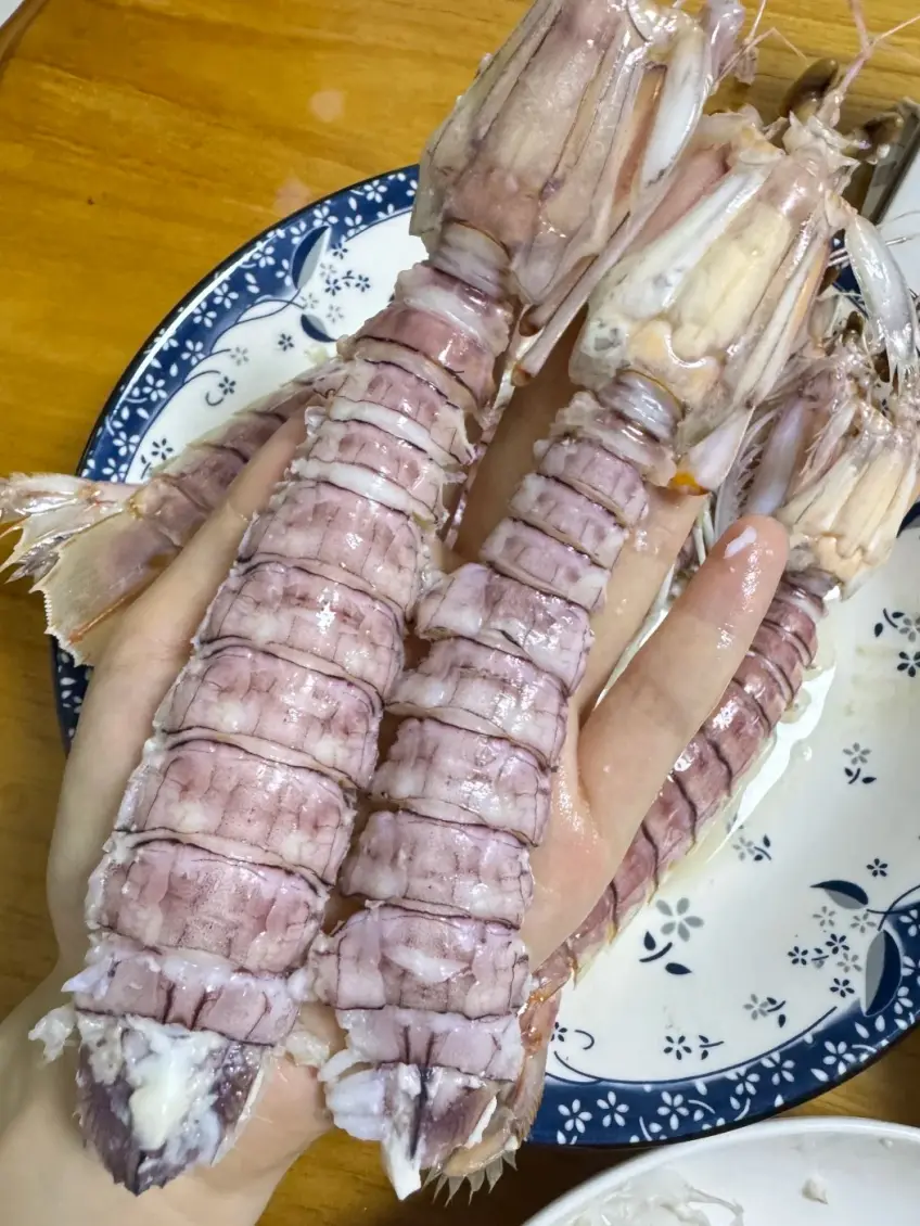 人手托起兩隻皮皮蝦餐桌示意