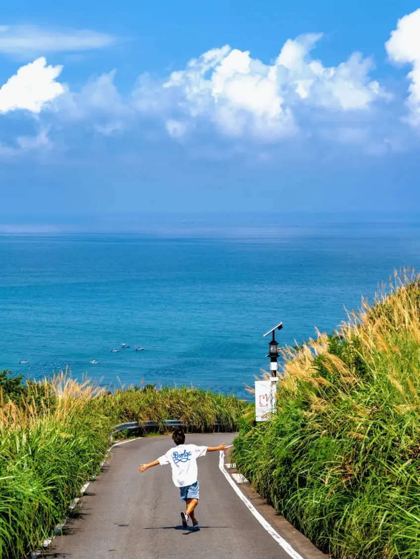 背影孩童張開雙臂走下沿海公路望海