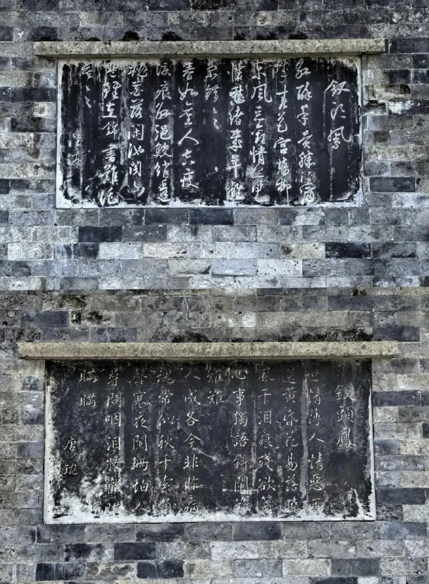 青磚牆上上下兩塊釵頭鳳詩詞黑色石刻