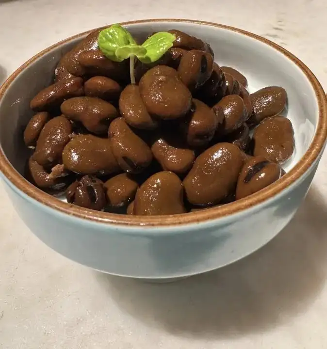 淺藍瓷碗盛滿醬色茴香豆點綴綠芽
