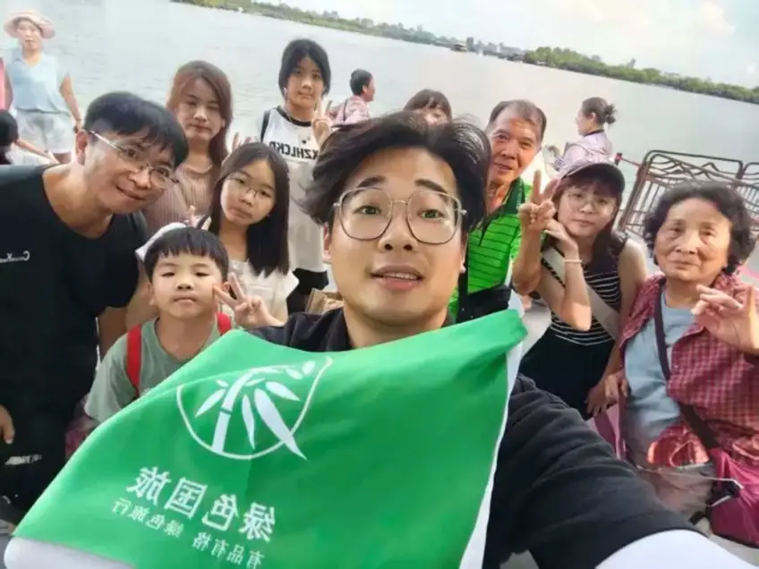 导游举旗与游客在湖畔码头自拍