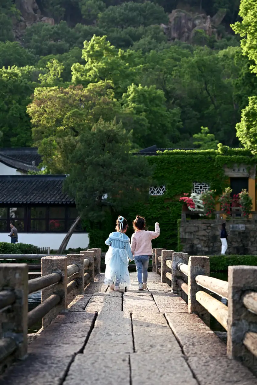 兩孩牽手走過石橋山景示意