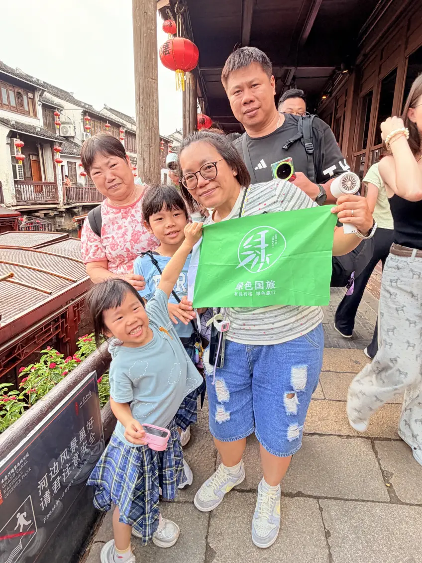 水鄉石徑旁家庭舉綠旗合影留念